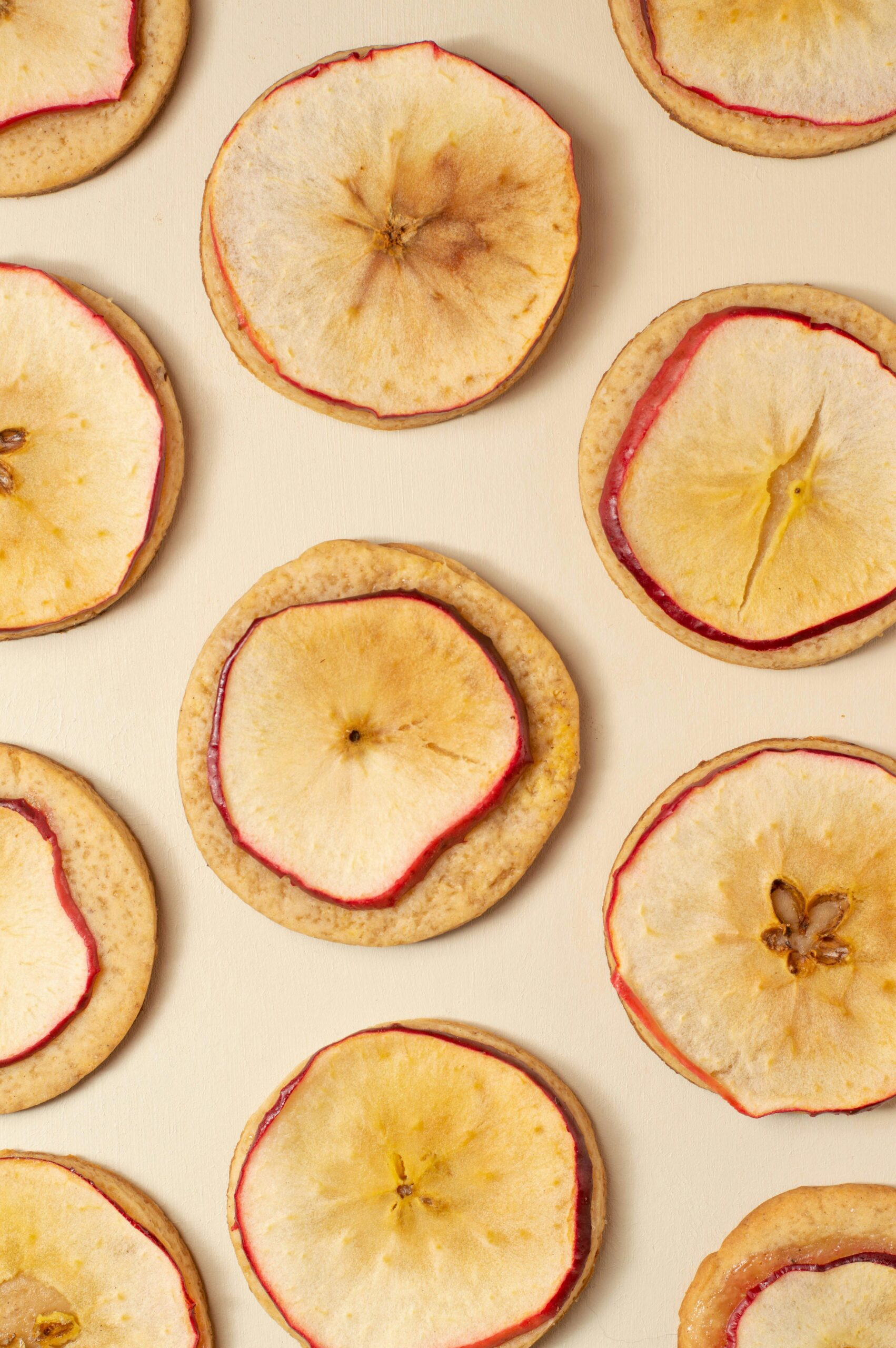 pexels photo 7633894 7633894 Top-down view of dried apple slices arranged on a beige surface, ideal for food photography.